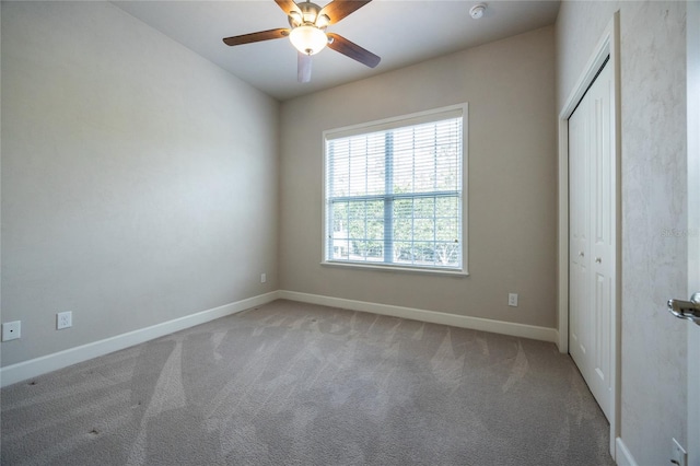 unfurnished bedroom featuring a ceiling fan, baseboards, a closet, and light colored carpet