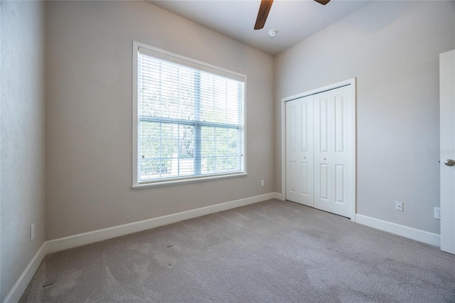 unfurnished bedroom featuring light carpet, ceiling fan, a closet, and baseboards