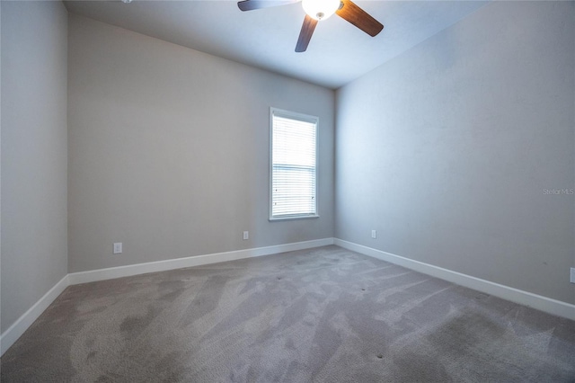 carpeted spare room featuring ceiling fan and baseboards