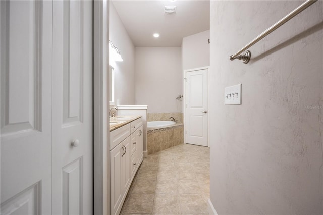 bathroom with a garden tub, tile patterned flooring, and vanity