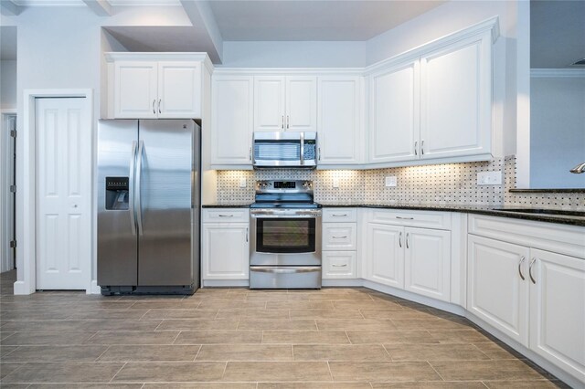 kitchen with stainless steel appliances, tasteful backsplash, a sink, and white cabinetry