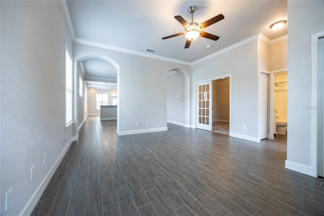 unfurnished living room featuring visible vents, ornamental molding, ceiling fan, dark wood-type flooring, and arched walkways