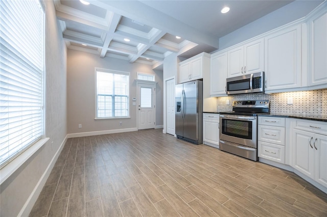 kitchen featuring dark countertops, decorative backsplash, stainless steel appliances, and beam ceiling