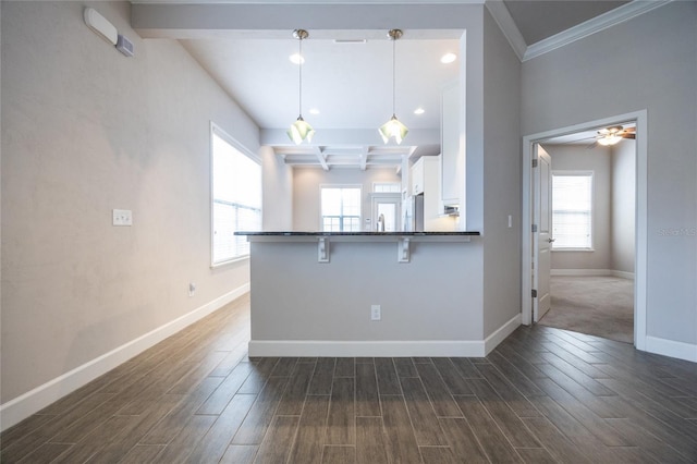kitchen with a breakfast bar area, beam ceiling, baseboards, white cabinets, and dark wood-type flooring