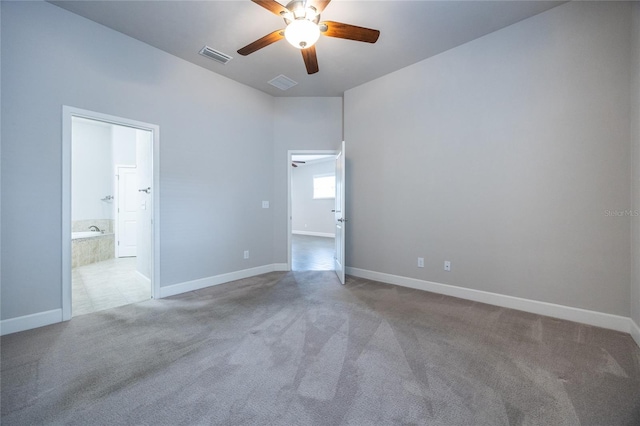 empty room with carpet floors, a ceiling fan, baseboards, and visible vents
