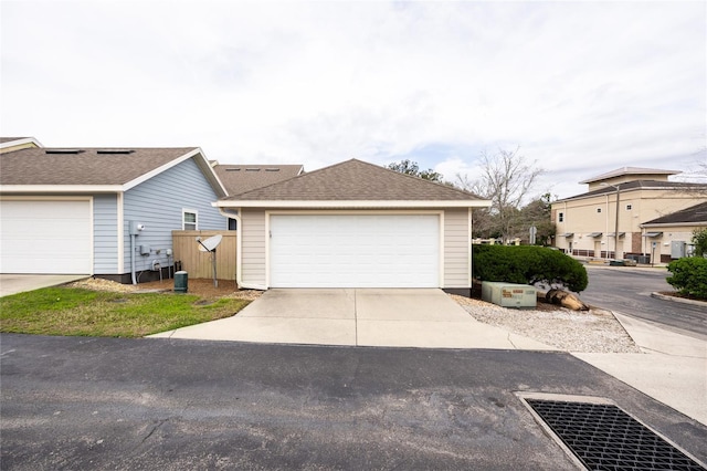exterior space with a shingled roof and a garage