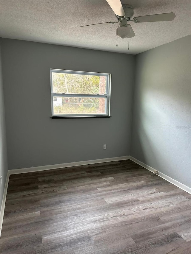 spare room featuring a textured ceiling, wood finished floors, and baseboards