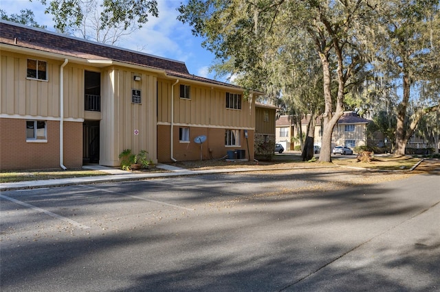 view of building exterior with uncovered parking and central AC unit