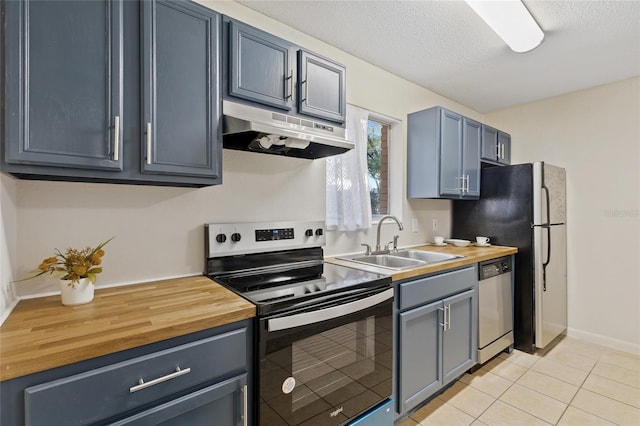 kitchen featuring appliances with stainless steel finishes, butcher block counters, a sink, and under cabinet range hood