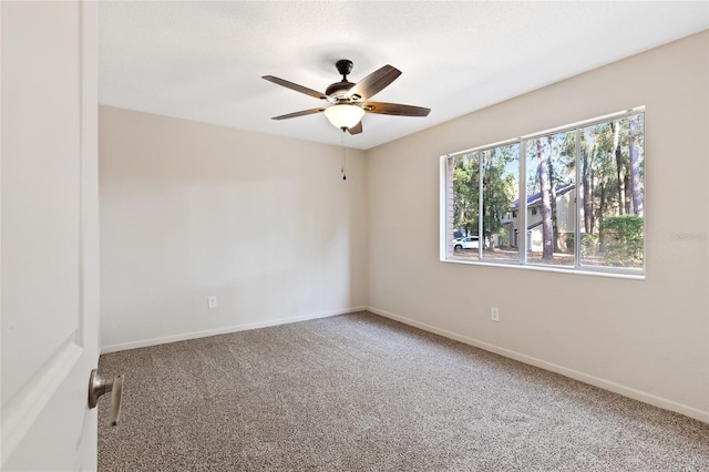 carpeted spare room with ceiling fan and baseboards