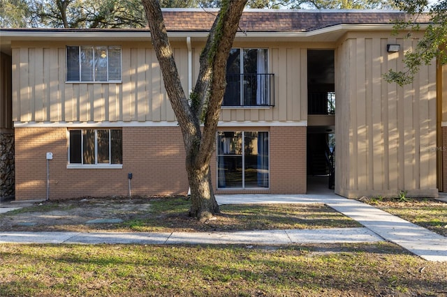 exterior space with brick siding, board and batten siding, and a shingled roof