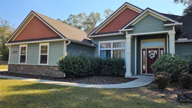 craftsman-style home featuring stone siding, roof with shingles, and a front yard