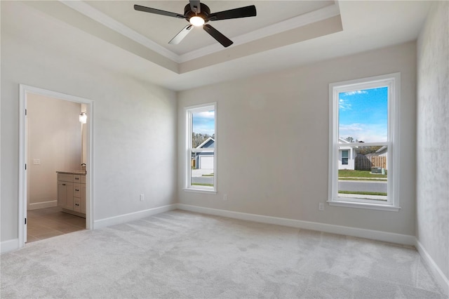 unfurnished bedroom with crown molding, a raised ceiling, light colored carpet, and connected bathroom