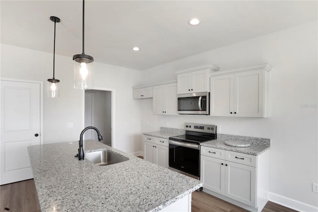 kitchen featuring a center island with sink, appliances with stainless steel finishes, dark wood-style flooring, white cabinetry, and a sink