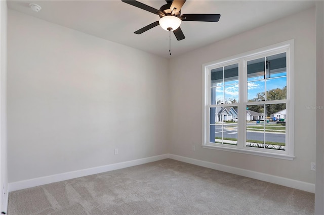 empty room featuring ceiling fan, baseboards, and light colored carpet