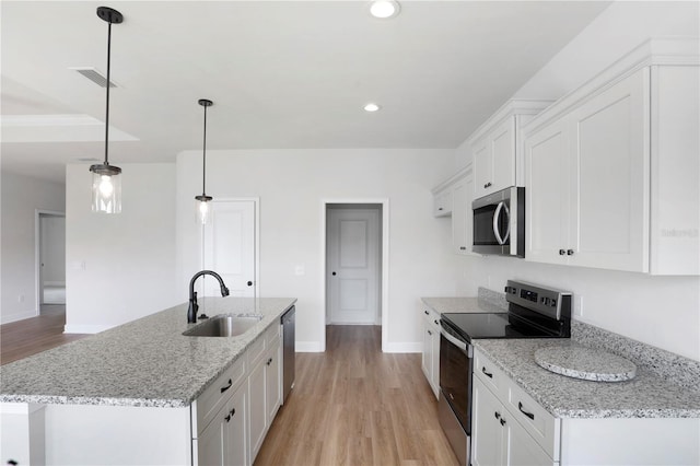 kitchen with light wood finished floors, visible vents, stainless steel appliances, white cabinetry, and a sink