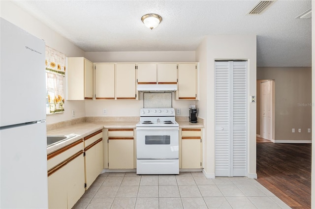 kitchen featuring light countertops, white appliances, visible vents, and cream cabinets