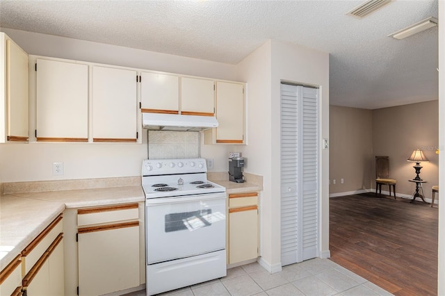 kitchen featuring visible vents, electric stove, light countertops, a textured ceiling, and under cabinet range hood