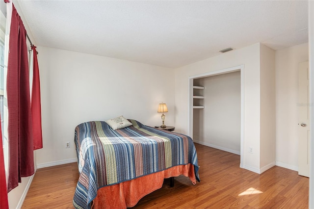 bedroom with visible vents, baseboards, and wood finished floors