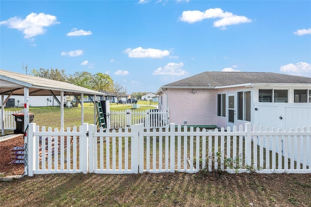 view of home's exterior featuring roof with shingles, a yard, stucco siding, a gate, and fence