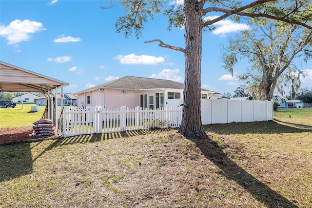 rear view of house featuring a yard, fence, and stucco siding