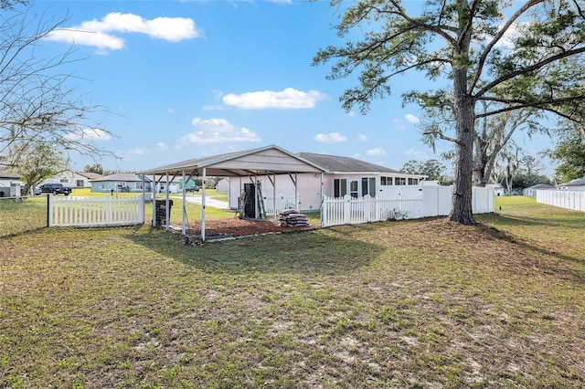 back of property featuring fence private yard, a lawn, and a detached carport