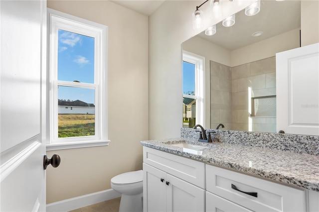 full bathroom with tile patterned flooring, toilet, vanity, baseboards, and a tile shower