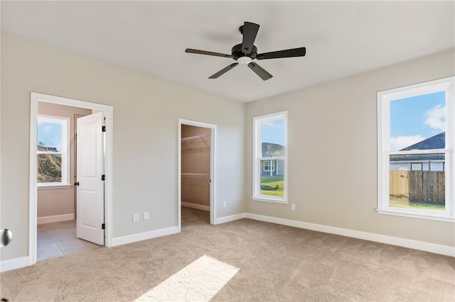 unfurnished bedroom with carpet, a spacious closet, and multiple windows