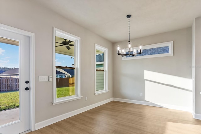 unfurnished dining area with baseboards, an inviting chandelier, and wood finished floors