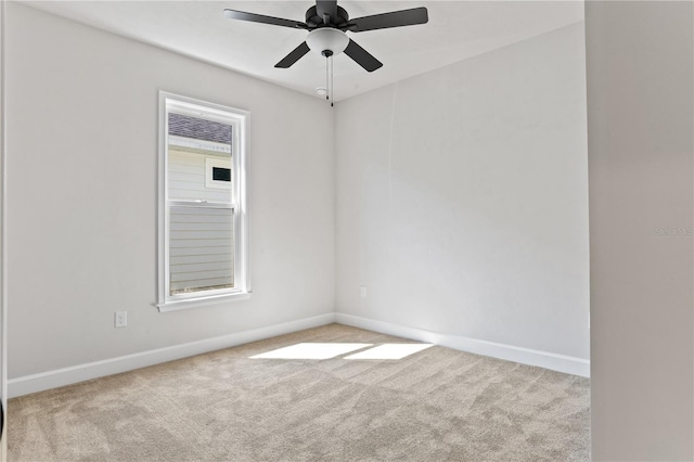 carpeted spare room with baseboards and a ceiling fan