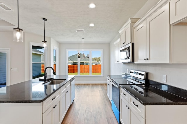 kitchen with wood finished floors, appliances with stainless steel finishes, a sink, and visible vents