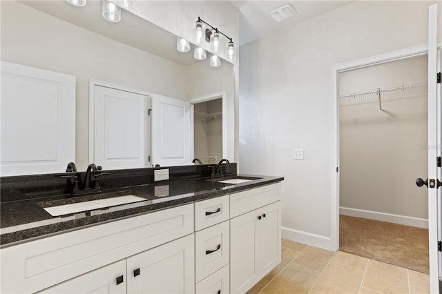 bathroom featuring double vanity, a spacious closet, a sink, and tile patterned floors