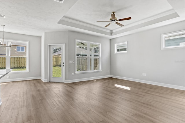 unfurnished room featuring a raised ceiling, a healthy amount of sunlight, and wood finished floors