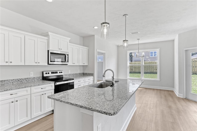 kitchen featuring light wood-style flooring, appliances with stainless steel finishes, a kitchen island with sink, white cabinets, and a sink