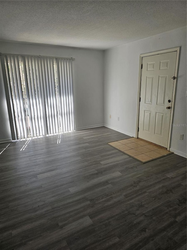 interior space with a textured ceiling, baseboards, and wood finished floors