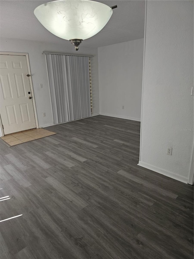 interior space featuring a textured ceiling, wood finished floors, and baseboards