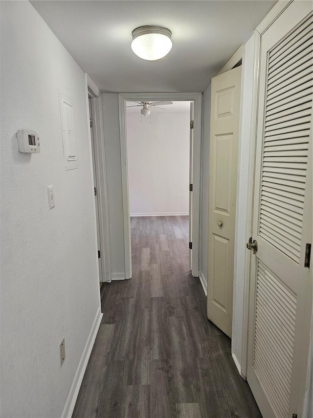 hall featuring dark wood-style flooring and baseboards