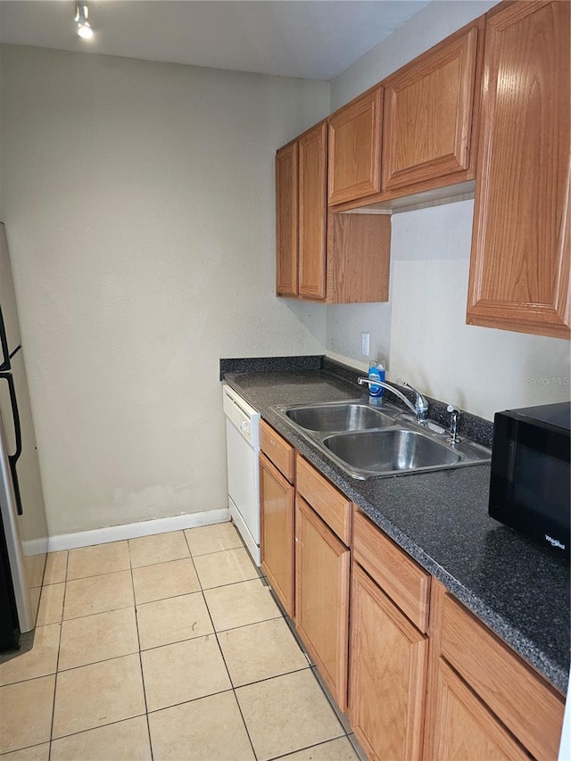 kitchen featuring refrigerator, light tile patterned floors, a sink, black microwave, and dishwasher