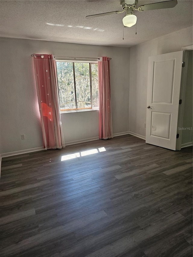 unfurnished room with a textured ceiling, baseboards, and dark wood-type flooring