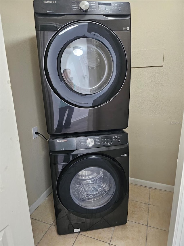 washroom featuring baseboards, stacked washer and dryer, laundry area, and tile patterned floors