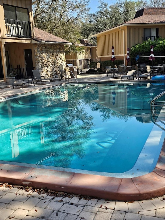 pool with a patio area and fence