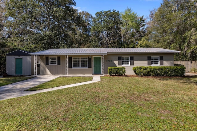 ranch-style home with metal roof, a front lawn, fence, and driveway