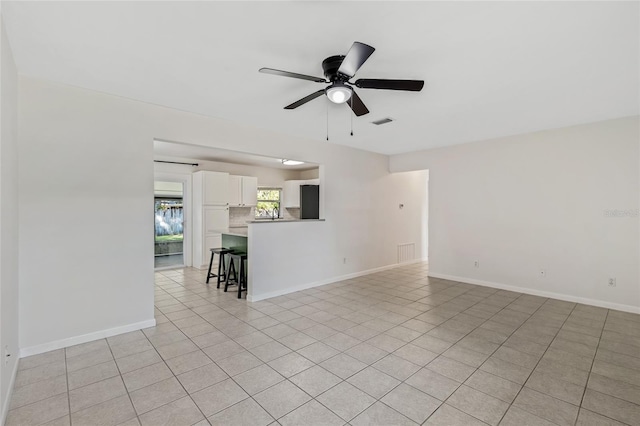 spare room with baseboards, visible vents, a ceiling fan, and light tile patterned flooring