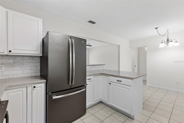 kitchen featuring freestanding refrigerator, white cabinetry, a peninsula, and decorative backsplash