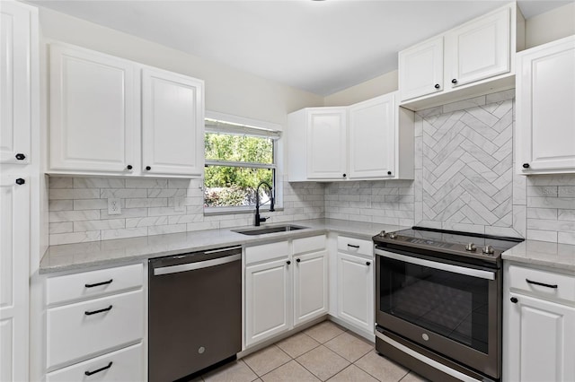 kitchen with light tile patterned floors, stainless steel appliances, a sink, white cabinetry, and tasteful backsplash