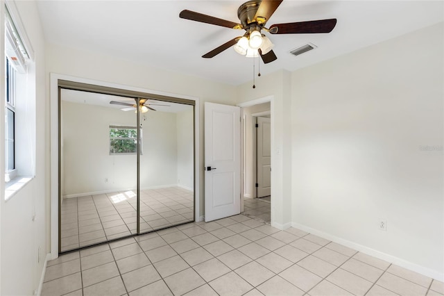 unfurnished bedroom with light tile patterned floors, a closet, visible vents, ceiling fan, and baseboards