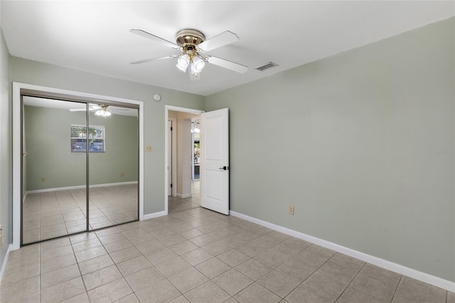 unfurnished bedroom with a closet, visible vents, a ceiling fan, light tile patterned flooring, and baseboards