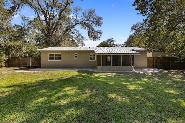 back of property featuring a sunroom, metal roof, fence, a yard, and a patio area