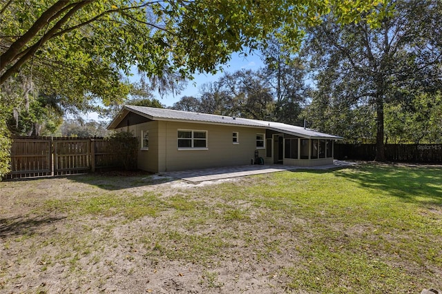 back of property with a sunroom, a fenced backyard, a lawn, and metal roof