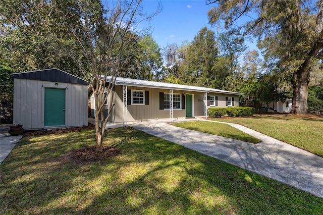 view of front of property featuring driveway, a shed, a front lawn, and an outbuilding